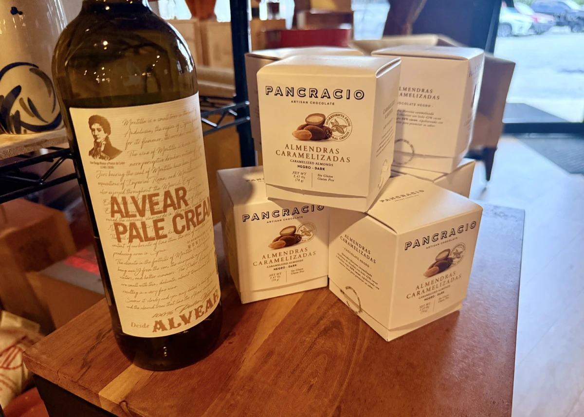 A bottle of Alvear Pale Cream from Montilla-Moriles beside boxes of Pancracio caramelised almonds in dark chocolate