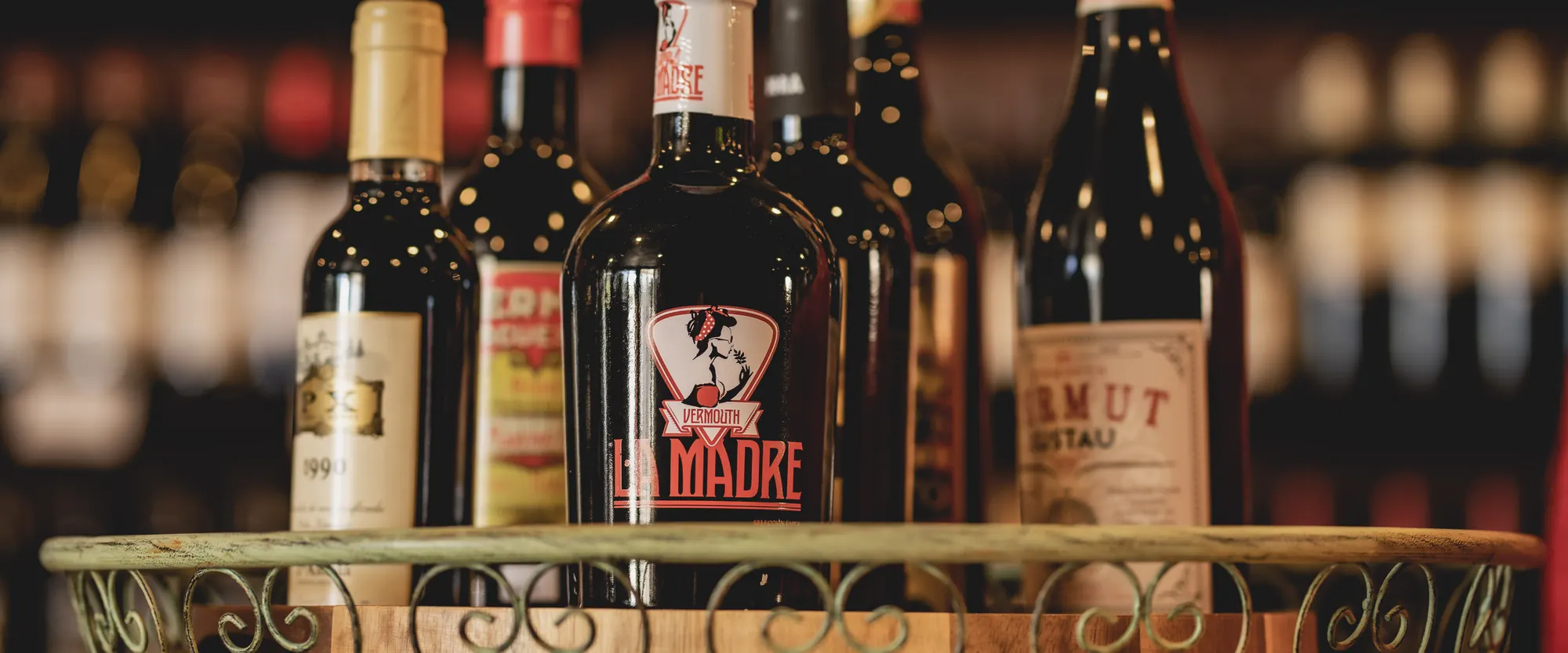 Bottles of Spanish vermouth and sherry, La Madre, Pedro Ximénez, and Lustau Vermut among them, in a wrought-iron basket at La Vid