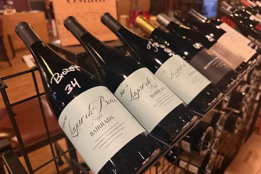Bairrada wines racked at La Vid: bottles angled in a wire rack, one priced 34 in white marker