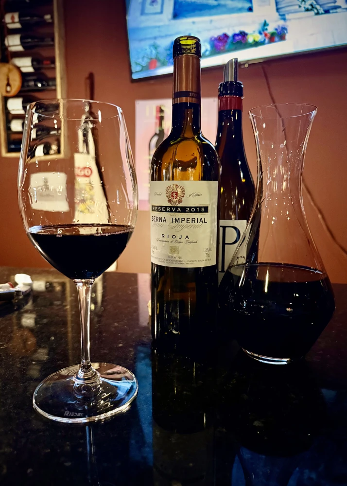 A glass of Rioja poured beside a bottle of Serna Imperial Reserva 2015 on the bar at La Vid