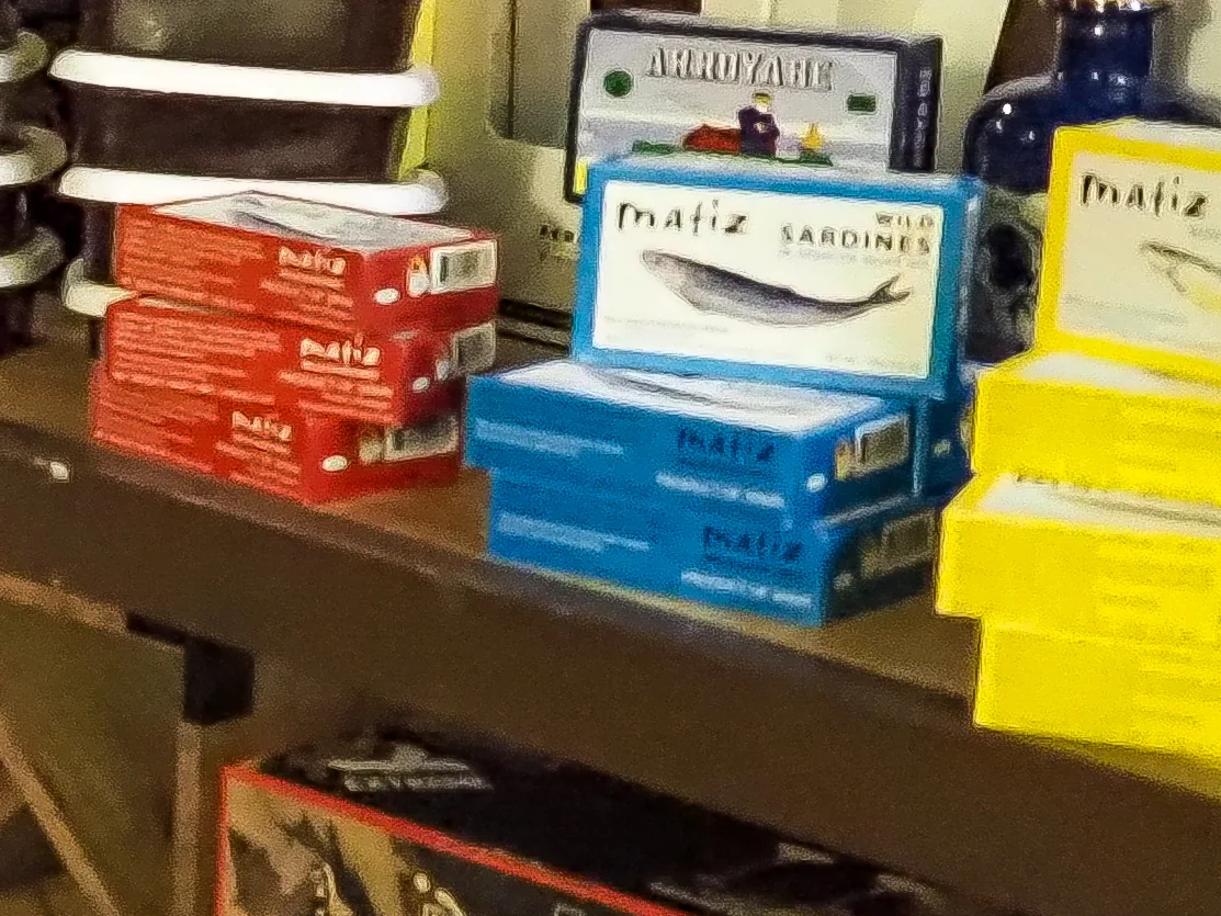 Stacks of blue Matiz wild sardine tins and red Matiz tins on a shelf at La Vid, with a tin of Arroyabe above